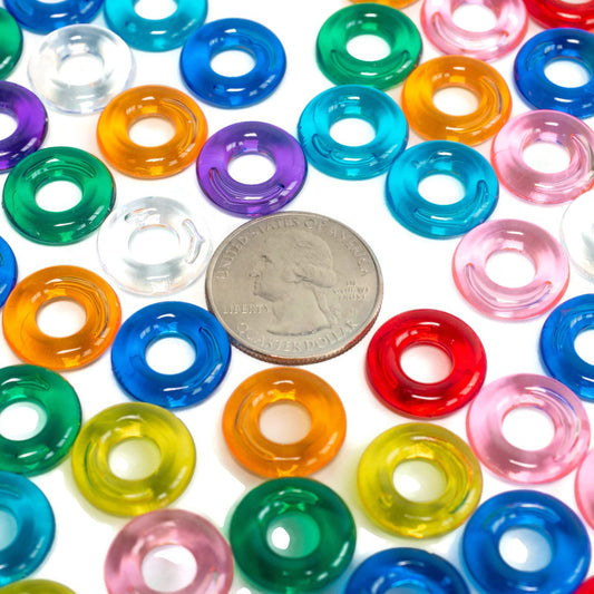 Colorful plastic rings with a quarter for size comparison on a white background