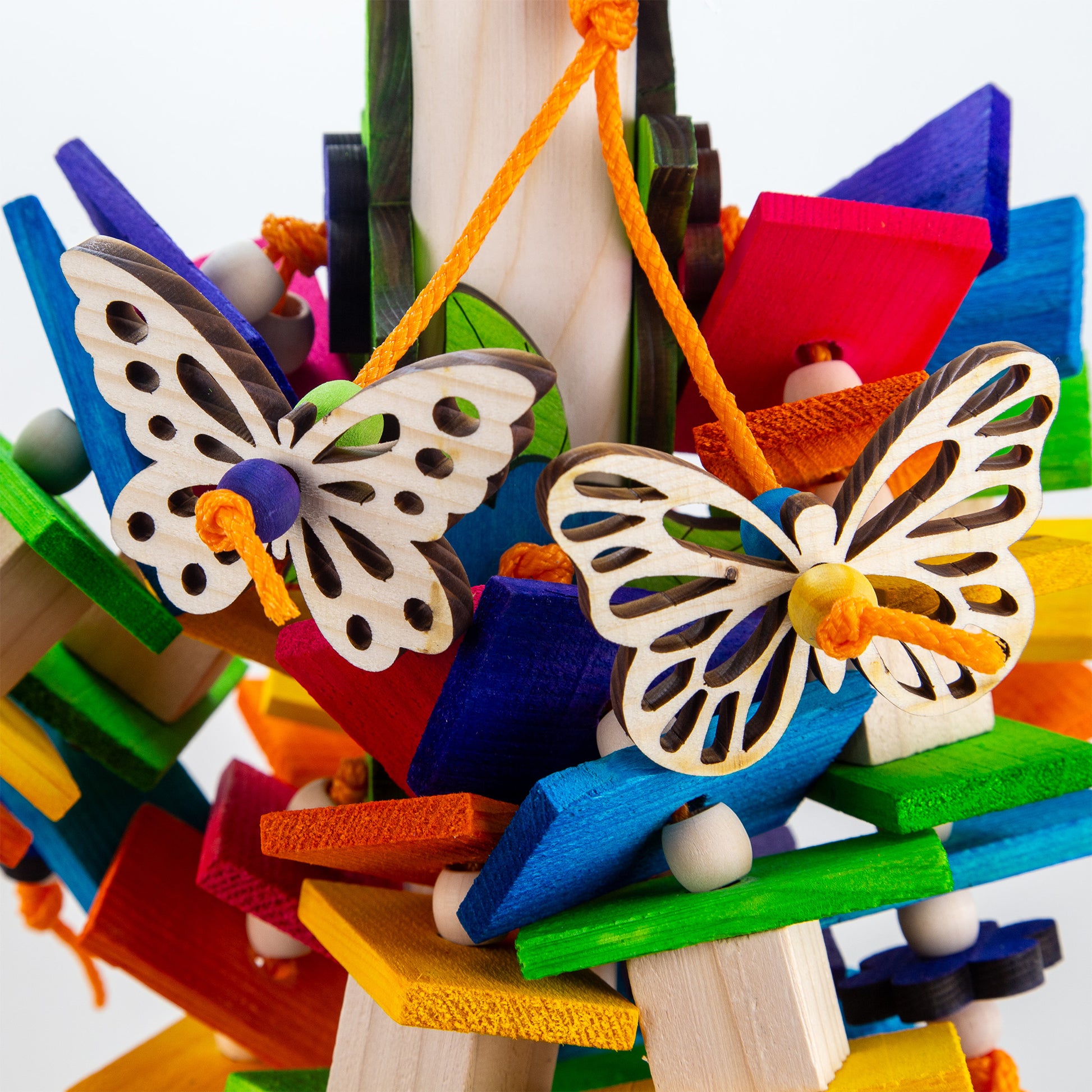 Colorful Pine wood bird toy with natural and colored blocks and slats featuring flower and butterfly shaped wood decorations.